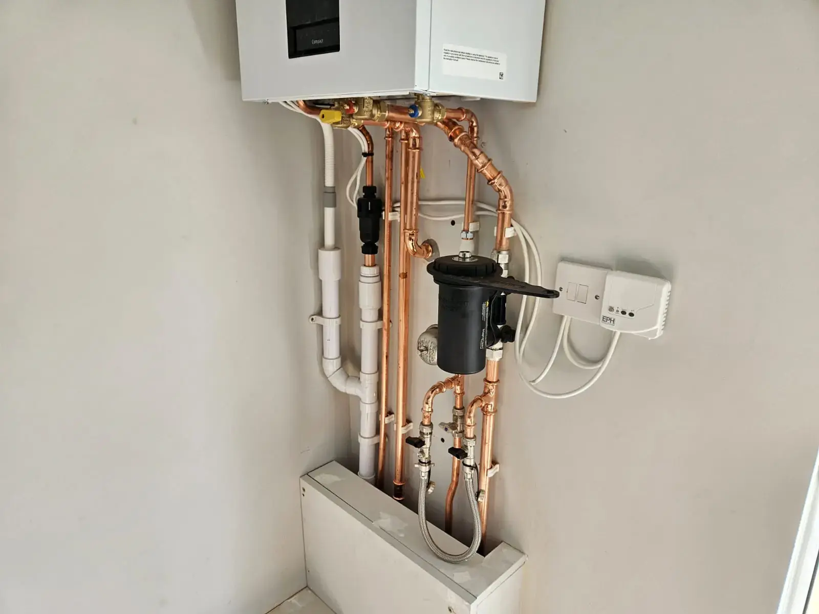 Newly installed combi boiler with neat copper pipework and a magnetic system filter