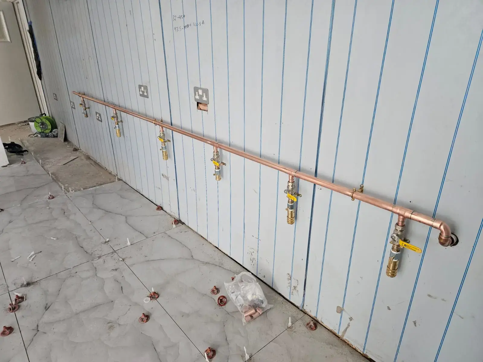 New copper gas pipework run along a commercial kitchen wall with yellow-handled isolation valves for each appliance