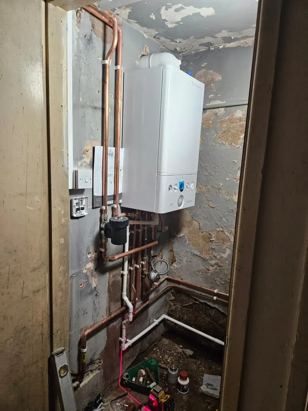 Wall-hung boiler in a cupboard with copper and plastic pipework and a heating controls wiring centre